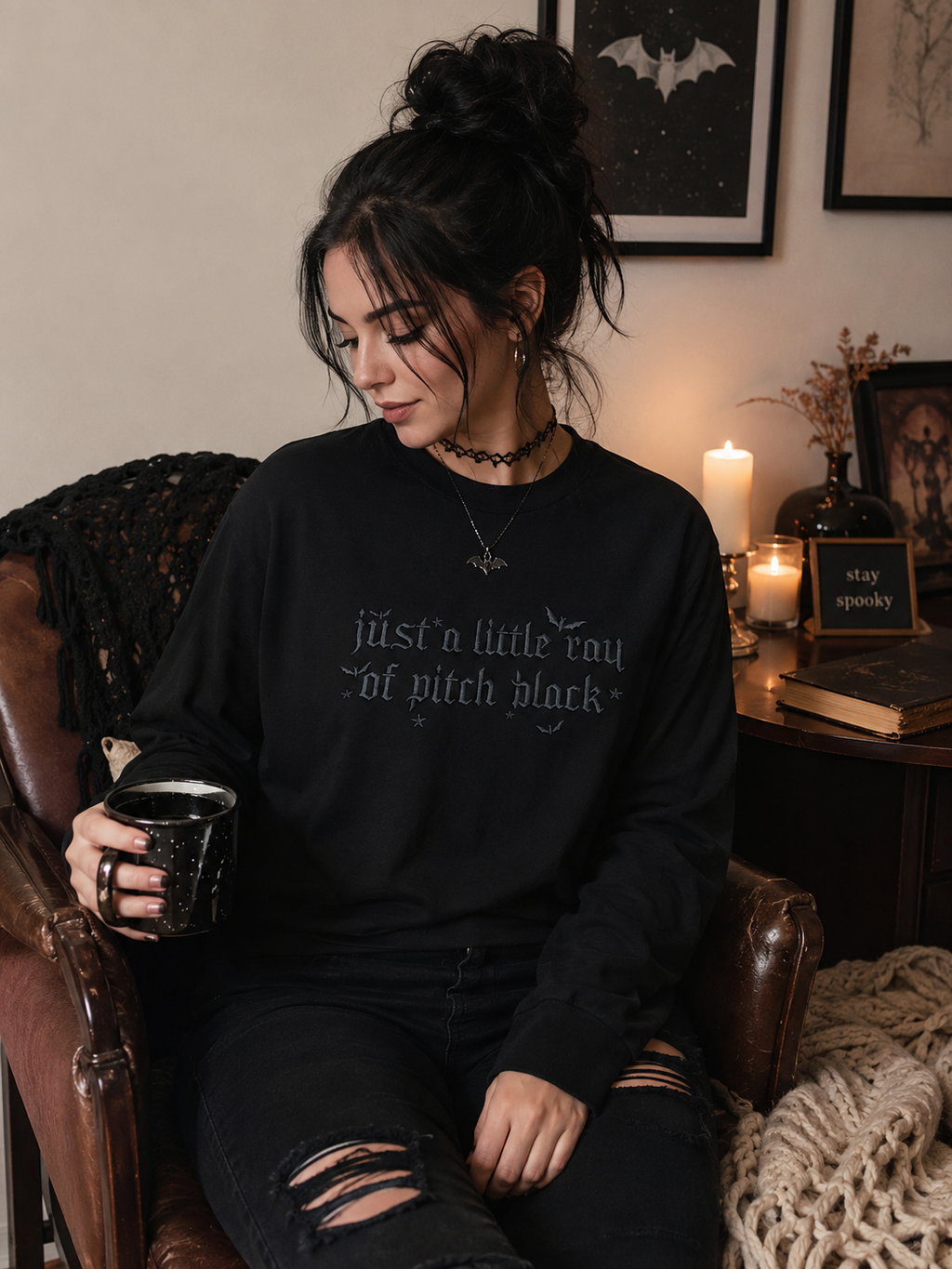 Model wearing black embroidered sweatshirt with 'just a little ray of pitch black' tonal embroidery